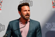 A man in a suit speaking at a podium during a public event