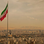 Iran’s Revenge Mission: Ivanka Trump Named Iranian flag waving over a city skyline with mountains in the background