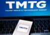 Smartphone displaying the Truth Social app on a laptop with TMTG logo in the background