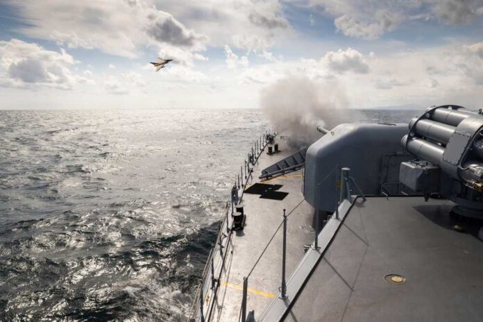 A,Frigate,Of,Navy,Makes,Missile,Launch,During,Fighting,With Naval ship firing a weapon into the ocean with a plane flying overhead