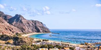 Scenic view of a beach with mountains and colorful buildings in the foreground