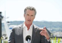 A man in a suit speaking at a press conference outdoors