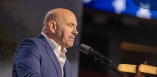 A man in a blue suit speaking into a microphone at an event