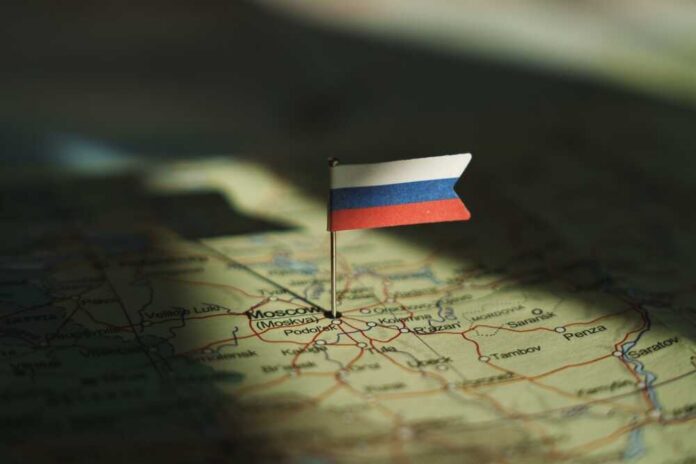 Russian,Federation,Flag,On,Russia,Map,Highlighted,By,Dramatic,Light. A small Russian flag pinned on a map of Moscow
