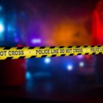 Mass Panic Hits Motorcycle Fest – How? Police crime scene tape with emergency lights in the background