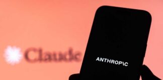A hand holding a smartphone displaying the word 'ANTHROPIC' against a blurred background