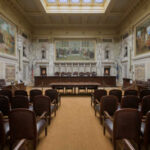 Interior view of a courtroom with wooden benches and large murals