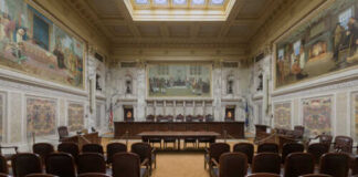 Interior view of a courtroom with wooden benches and large murals