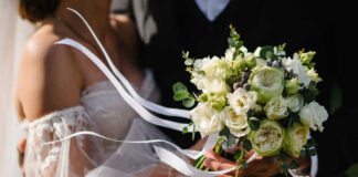 Bride holding white flower bouquet with ribbons