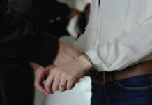 Person in handcuffs wearing jeans and white shirt