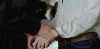 Person in handcuffs wearing jeans and white shirt