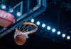 Basketball swishing through hoop under arena lights