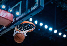 Basketball swishing through hoop under arena lights