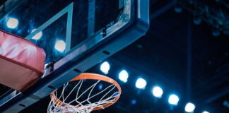 Basketball swishing through hoop under arena lights
