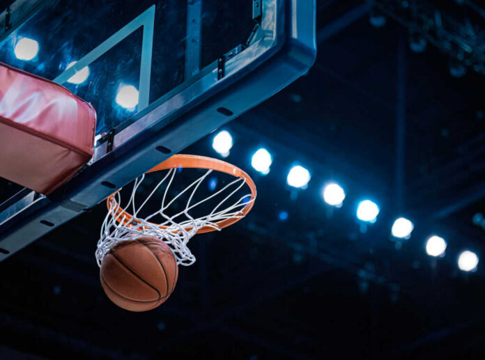 Basketball swishing through hoop under arena lights