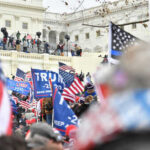 DOJ Backs Refunds — Hill Erupts Crowd with flags near a government building