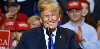 smiling man in suit speaking at a rally