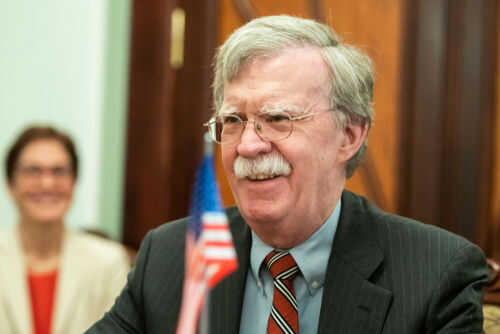 john-bolton1163128426jpg Man with glasses smiling near small American flag
