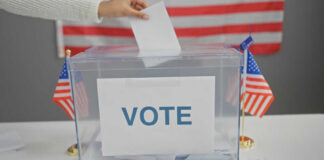 Hand placing ballot in box with American flags