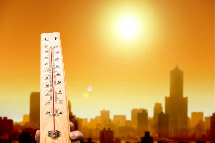 Heat,Wave,In,The,City,And,Hand,Showing,Thermometer,For Thermometer displaying high temperature against a sunset city skyline