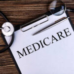 Runaway Fraudster Dragged Back to Court A document labeled 'Medicare' with a stethoscope and magnifying glass on a wooden surface