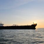 Cargo ship sailing on the ocean during sunset