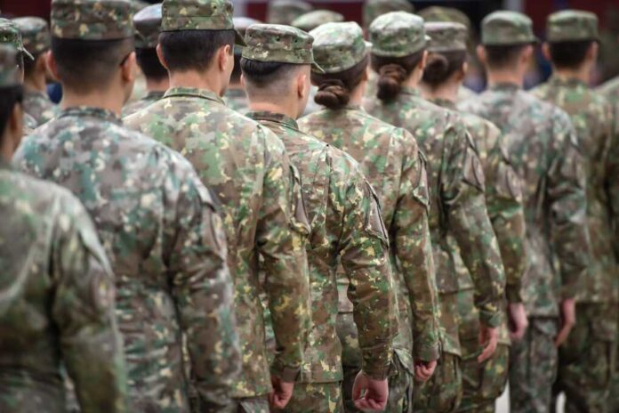 Soldiers,In,Marching,Formation,During,Military,Recruitment Soldiers in camouflage uniforms standing in formation from behind