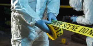 forensic investigators unrolling yellow barrier tape at night