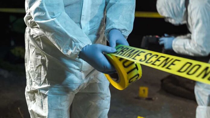 A,Forensic,Scientist,Rolling,Out,Police,Tape,At,A,Crime forensic investigators unrolling yellow barrier tape at night