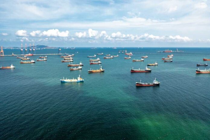 Aerial,View,Of,Numerous,Oil,And,Gas,Tankers,Anchored,In Aerial view of numerous cargo ships anchored in a blue ocean