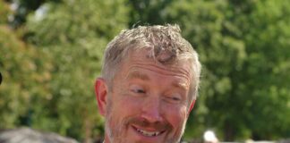 A smiling man in a suit engaging in conversation outdoors