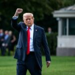 A political figure raising a fist while walking outdoors