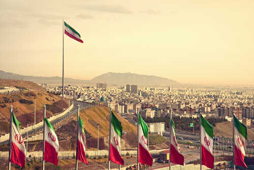 Set,Of,Iran,Flags,In,Front,Of,Tehran,Skyline,And View of Iranian flags with a city and mountains in the background