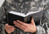 Woke Purge Or Cleanup? Pentagon Slashes Faiths Person in uniform holding an open Bible