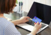 Paycheck ‘Victory’ Hides A Painful Bill Person holding a credit card while using a laptop