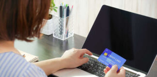Person holding a credit card while using a laptop