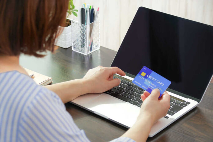 Person holding a credit card while using a laptop