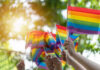 Corporate Pride Campaigns: All Logo, No Help Hands waving rainbow pride flags outdoors
