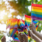 Hands waving rainbow pride flags outdoors