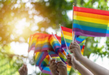 Hands waving rainbow pride flags outdoors