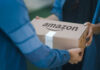 Two people exchanging an Amazon package, outdoors.