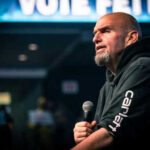 Fetterman’s Criticism Sparks New Democratic Rift Man speaking into microphone on stage.