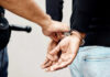 Police officer handcuffing a person with hands behind back