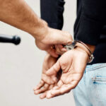 Police officer handcuffing a person with hands behind back