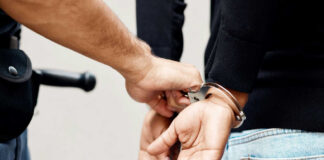 Police officer handcuffing a person with hands behind back