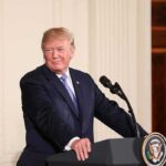 Dinner Mic Drop: 2028 Tease Ignites Frenzy man at podium with presidential seal