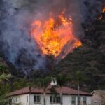 Spain Eases Fires — Legal Switch Missing Wildfire burning on a hillside near homes
