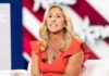 ‘Sacrifice’ Firestorm: Greene Torches Hegseth Woman speaking on stage in an orange dress