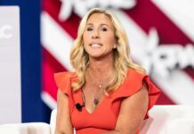 ‘Sacrifice’ Firestorm: Greene Torches Hegseth Woman speaking on stage in an orange dress