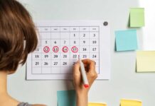 Person marking dates on a calendar with a red marker